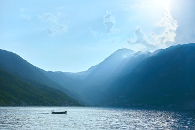 Boat with fishermen floats on the sea against the backdrop of mountains in montenegro