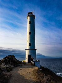 Lighthouse by sea against sky