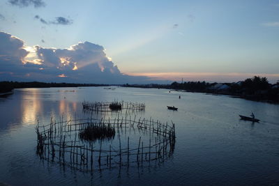 High angle view of silhouette abandoned fence in river against sky during sunset