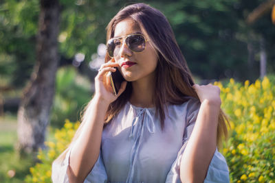 Portrait of beautiful young woman wearing sunglasses outdoors