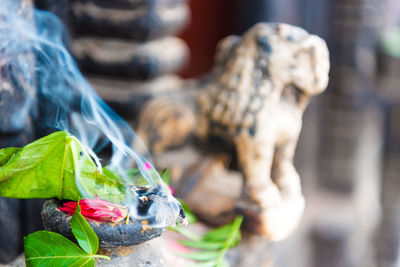 Close-up of burning incense by sculpture outdoors