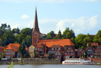 Houses by river and buildings against sky