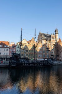 Sailboats in river by buildings against sky in city