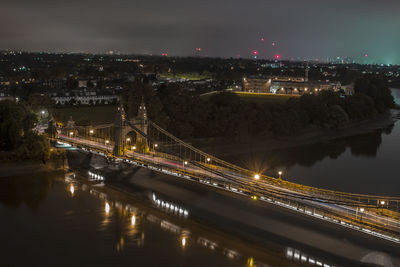 Illuminated bridge over river at night