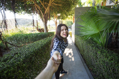 Portrait of smiling young woman against trees