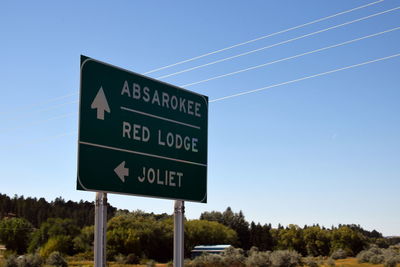 Low angle view of road sign against clear blue sky