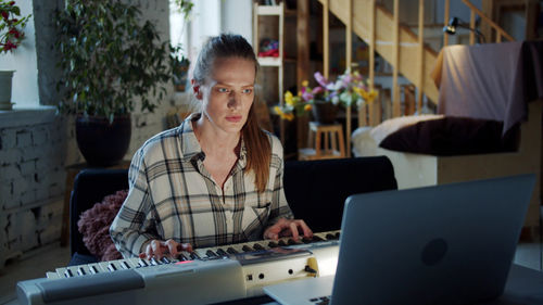 Woman learning piano from laptop