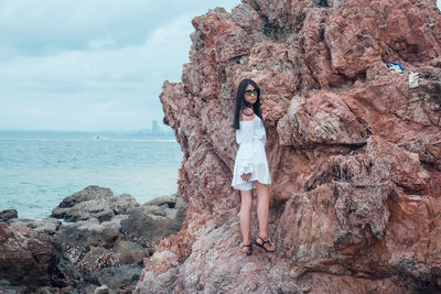 Portrait of woman standing on rock by sea