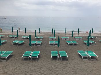 Empty chairs on beach against sky