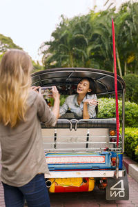 Woman taking photo of her friend in auto rickshaw