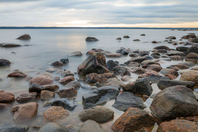 Rocks on beach against sky during sunset