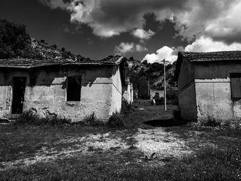 Old houses on field against sky