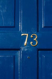 House number 73 on a blue wooden front door in london 