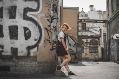 Full length of woman standing against buildings in city