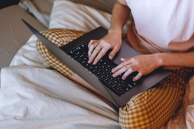 Midsection of man using mobile phone on bed