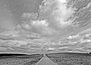 Road amidst field against sky