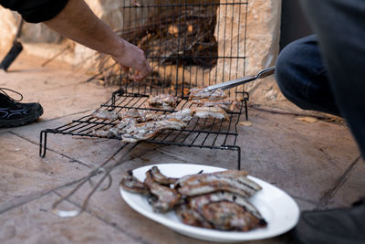 Two unrecognizable men are taking the cooked meat from the grill after the barbecue. close up.