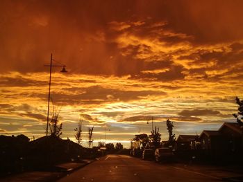 Silhouette electricity pylons against sky during sunset