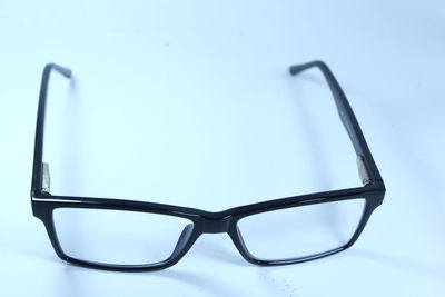Close-up of eyeglasses on table against blue background