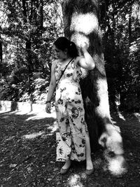 Full length of woman standing by tree trunk