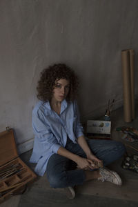 Young woman sitting on wall at home