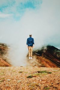 Rear view of man walking on mountain against sky