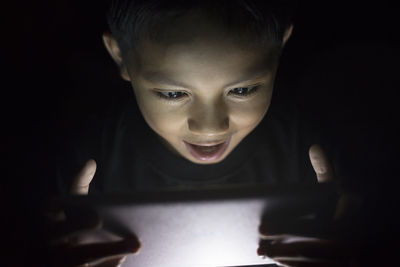 Boy using digital tablet in darkroom