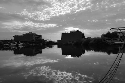 Reflection of buildings in lake against sky during sunset