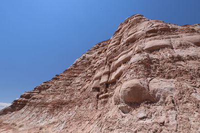 Low angle view of rock formation against clear blue sky