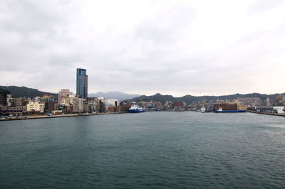 City at waterfront against cloudy sky