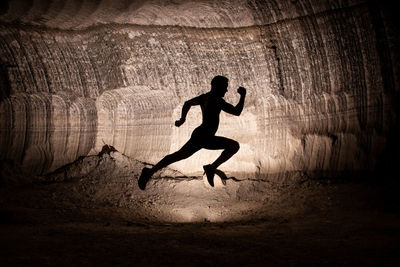 Side view of silhouette man jumping in tunnel