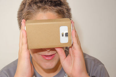 Close-up of boy looking in smart phone through cardboard virtual reality simulator