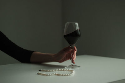 Midsection of woman holding wine glass on table