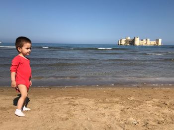 Boy on beach against sky