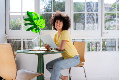 Smiling woman sitting on table at home