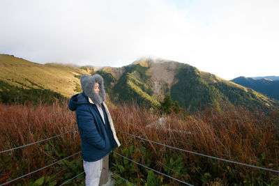 Woman standing by railing against plants during winter