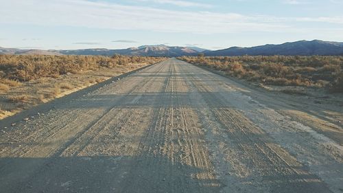 Road leading towards mountains against sky