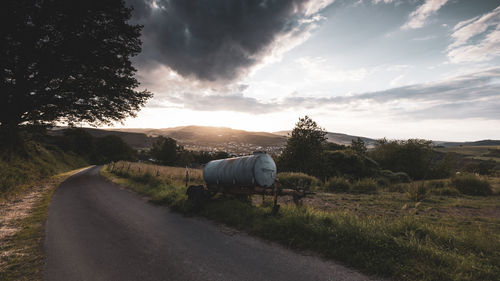 Rear view of man walking on road against sky during sunset