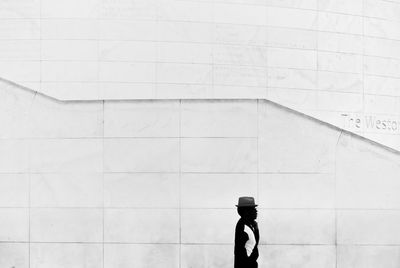 Side view of man walking against wall