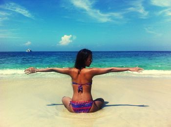 Rear view of woman on beach against sky