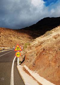 Road by mountain against cloudy sky