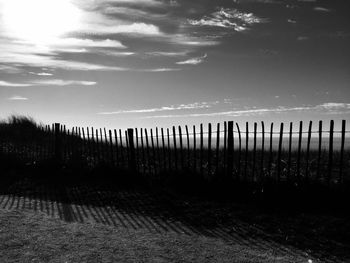 Wooden fence on field against sky