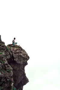 Man on rock by mountain against sky