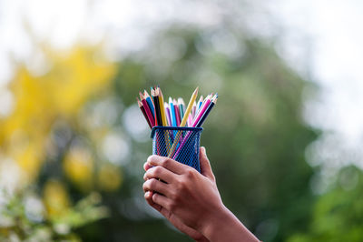 Midsection of person holding multi colored umbrella