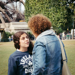 Mother and daughter talking while standing at park