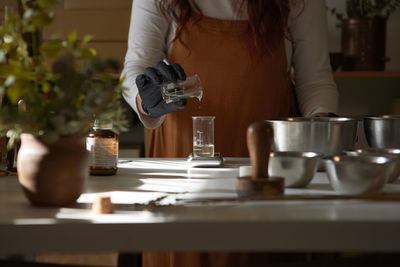 Midsection of woman standing by coffee cup on table