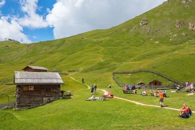 Hikers resting on a meadow at a mountain lodge in seceda in val garden, italy