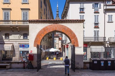 Rear view of people walking on street amidst buildings in city