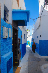 Rear view of woman on alley amidst buildings in city