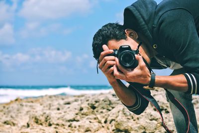 Close-up of man photographing camera on beach